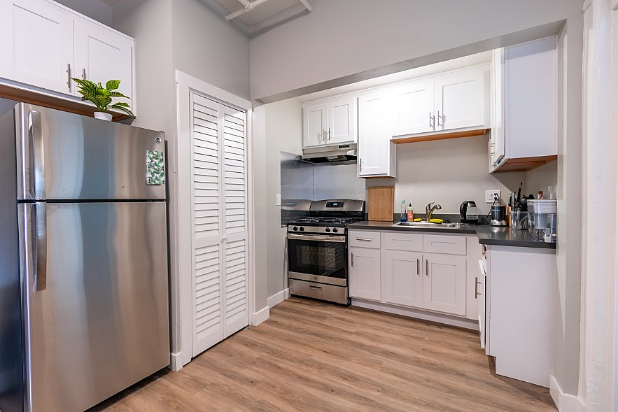 Modern kitchen with sleek stainless steel appliances, white cabinetry, and wood flooring.