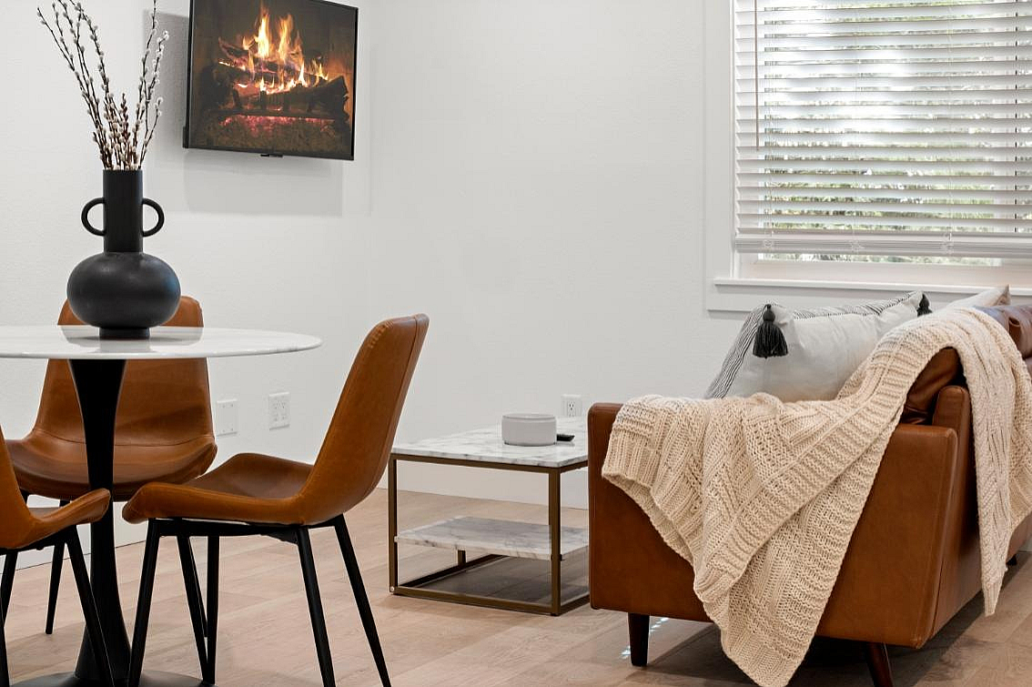 Elegant and modern open-concept living space with rich brown leather furnishings, sleek kitchen with stainless steel appliances, and cozy dining area, perfect for contemporary lifestyles.