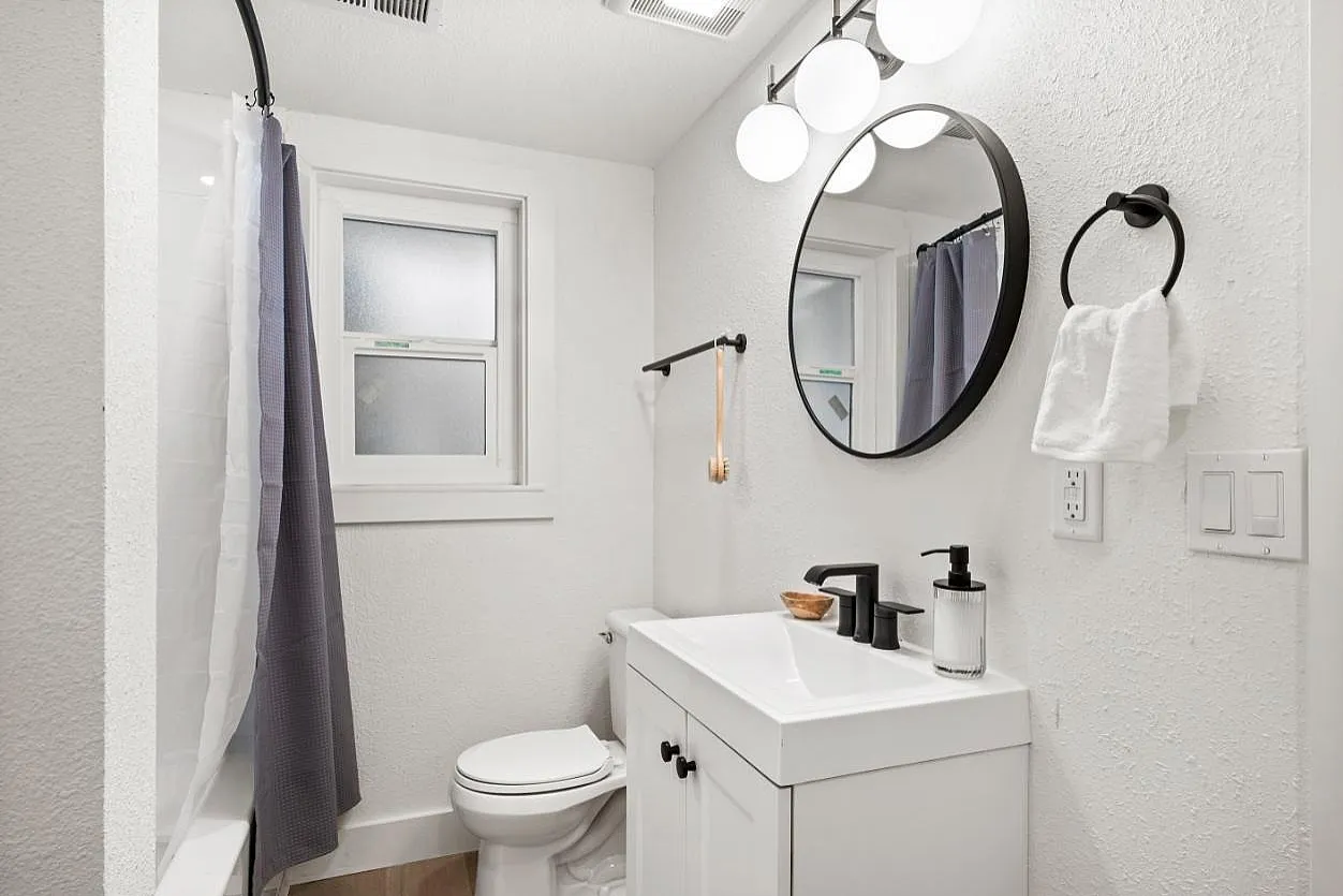 Elegant bathroom design featuring sleek fixtures, round mirrors, and a bright, modern aesthetic with stylish lighting.