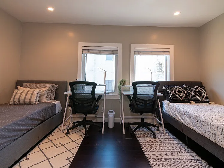 Inviting bedroom space with twin beds, dual workstations, modern decor, and abundant natural light.