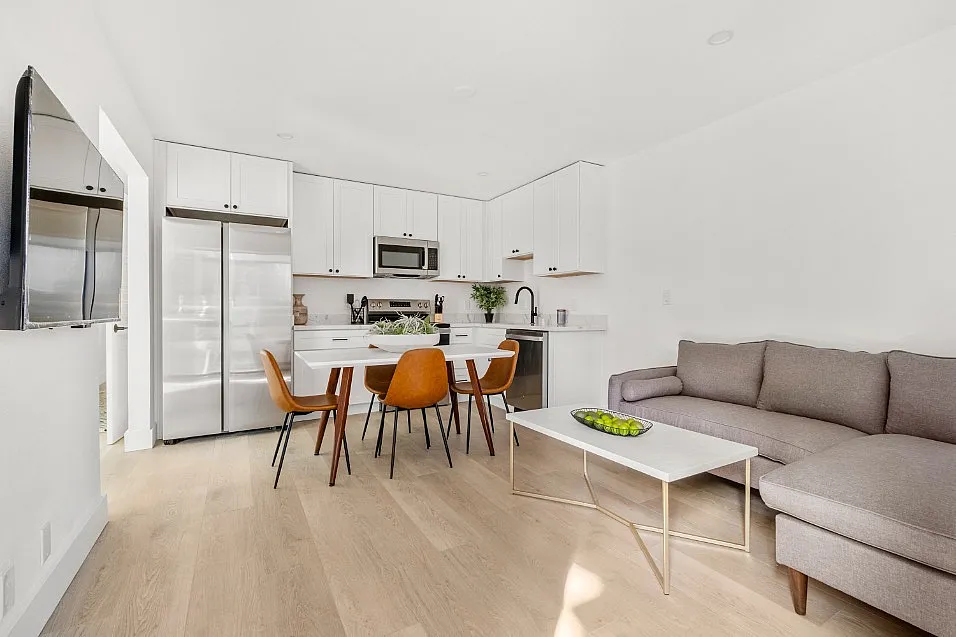 Bright and modern open-concept living area featuring a chic kitchen with stainless steel appliances, cozy seating, and stylish dining space.