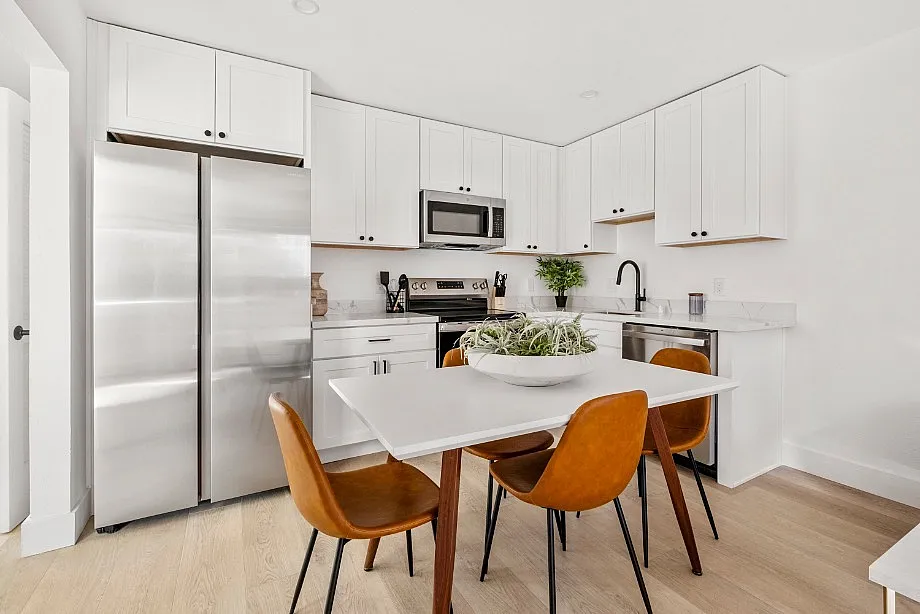 Modern kitchen space with sleek stainless steel appliances, elegant white cabinetry, and cozy dining area with stylish chairs, offering a perfect blend of functionality and aesthetics.
