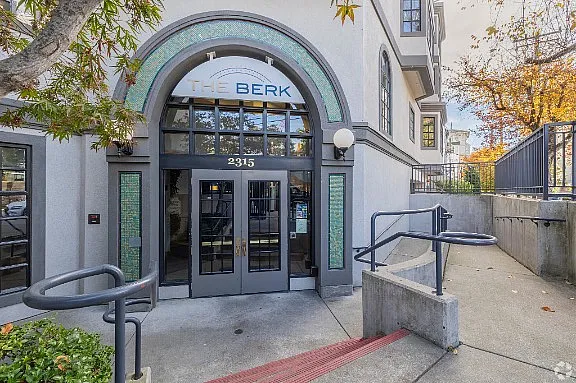 Inviting entrance of The Berk apartment complex with elegant arched doorway and vibrant glass accents.