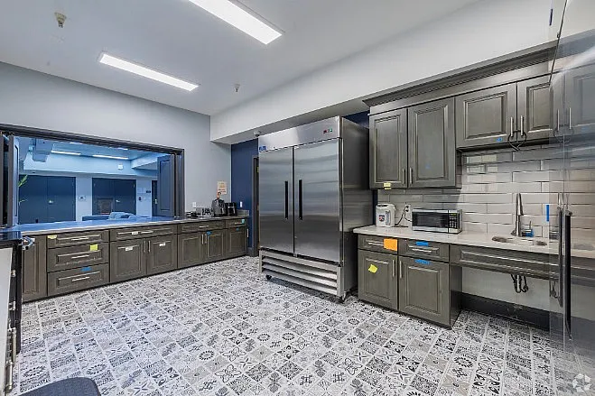 Modern kitchen with sleek gray cabinets, large stainless steel refrigerator, and patterned tile flooring.
