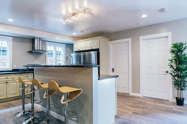 Elegant modern kitchen with sleek countertops, stylish bar stools, and stainless steel appliances, perfect for entertaining.