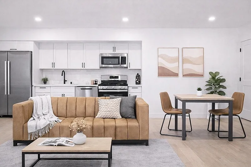 Modern open-concept living space with sleek kitchen, cozy tan sofa, and chic dining area, perfect for stylish urban living.