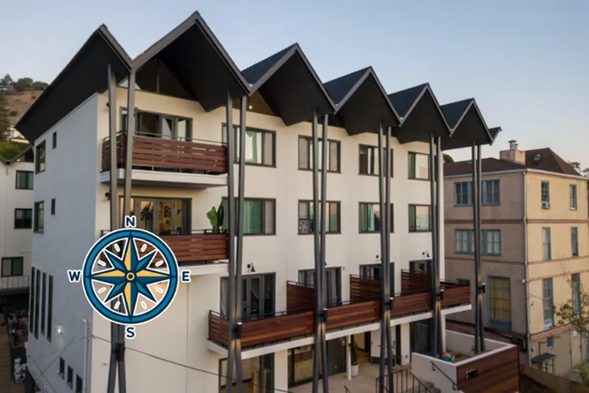 Modern three-story apartment building with distinct pitched roofs and spacious balconies, set against a picturesque hillside backdrop.