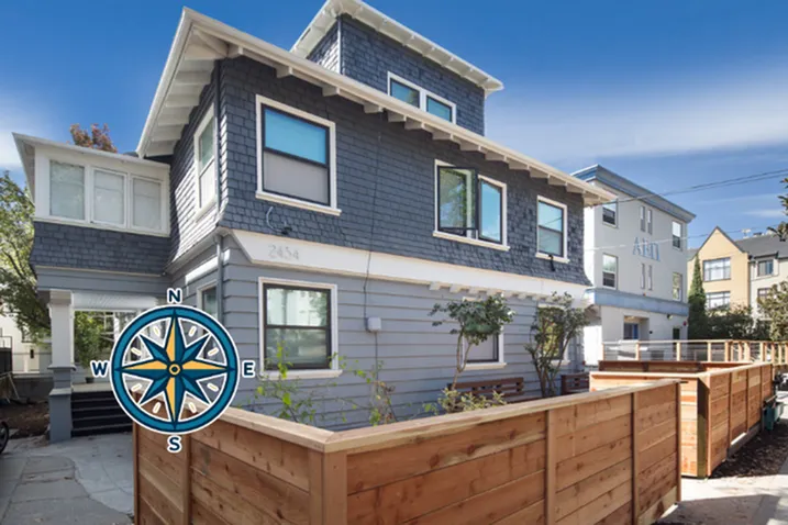Charming multi-story home with a modern exterior, surrounded by a cozy wooden fence and lush greenery, under a clear blue sky.