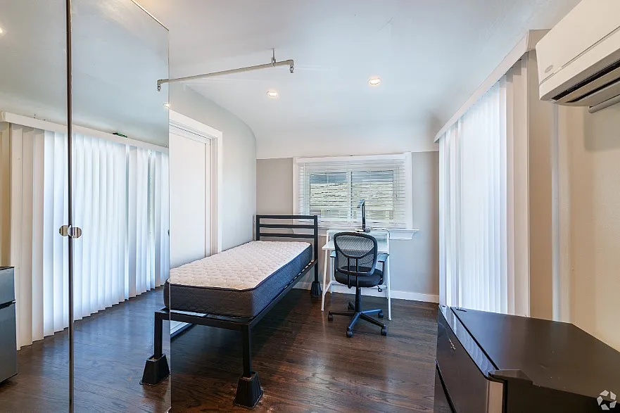 Bright and airy bedroom with a modern single bed, sleek desk, and hardwood floors, ideal for maximizing comfort and productivity.