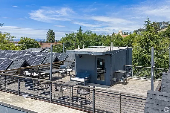 Chic rooftop deck with solar panels, comfortable outdoor seating, and scenic views of lush greenery.