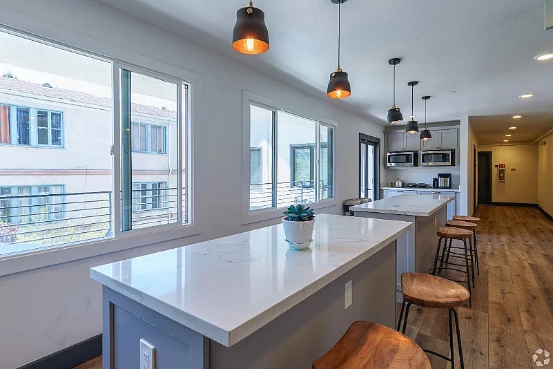 Bright, modern kitchen with sleek marble countertops, stylish pendant lighting, and bar seating.