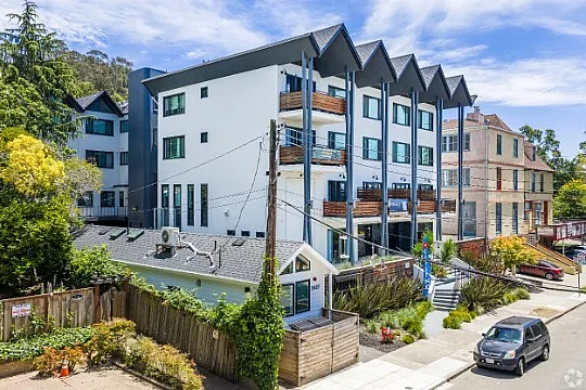 Modern apartment building with unique architecture, featuring balconies and lush landscaping in a vibrant neighborhood.