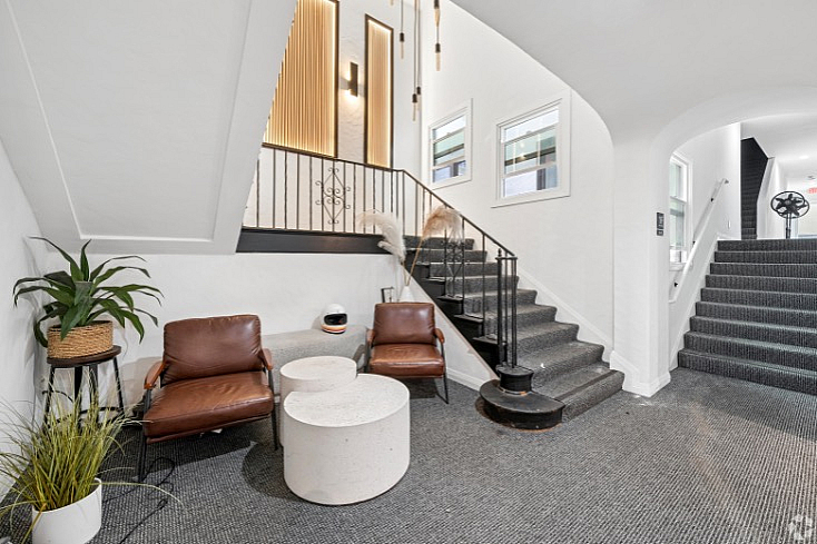 Elegant and cozy lobby area featuring modern seating, stylish staircase, and warm lighting accents.
