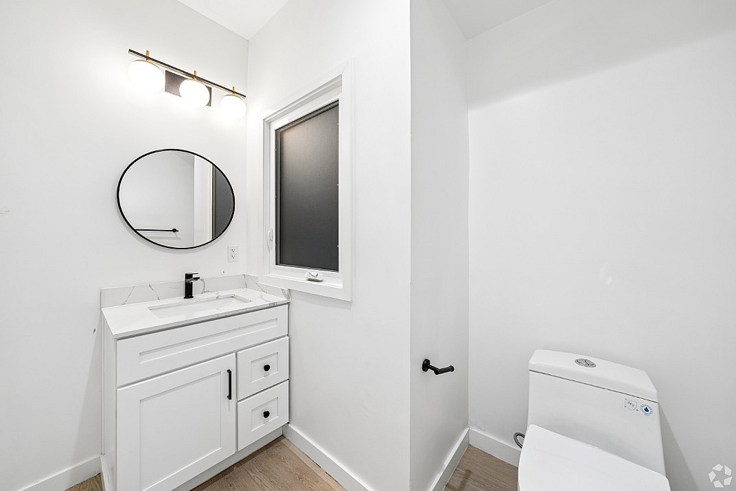 Modern bathroom with elegant white vanity, round mirror, and bright lighting.