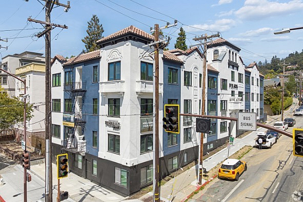 Charming urban apartment building with modern architecture, featuring elegant balconies and located at a bustling city intersection.