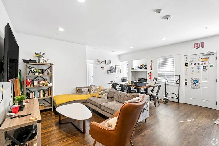 Inviting living space with stylish furnishings, cozy sectional sofa, modern armchair, and hardwood floors, ideal for vibrant gatherings or quiet relaxation.