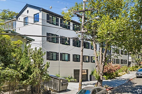 Charming multi-story apartment building with lush greenery, situated in a picturesque neighborhood with tree-lined streets.