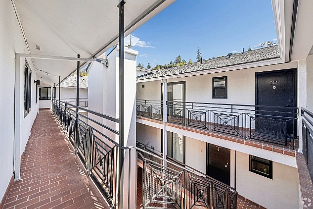 Charming apartment exterior with elegant railings, brick walkway, and scenic views, offering a welcoming atmosphere.
