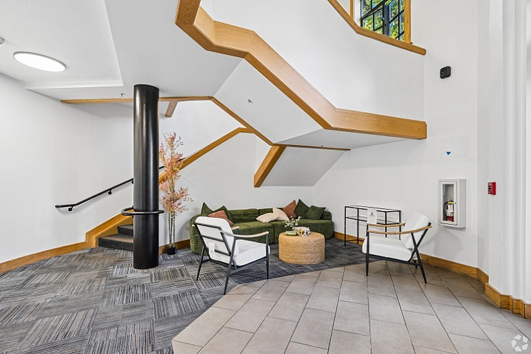 Chic apartment lobby featuring modern seating under a stylish wooden staircase, offering a welcoming and contemporary atmosphere.