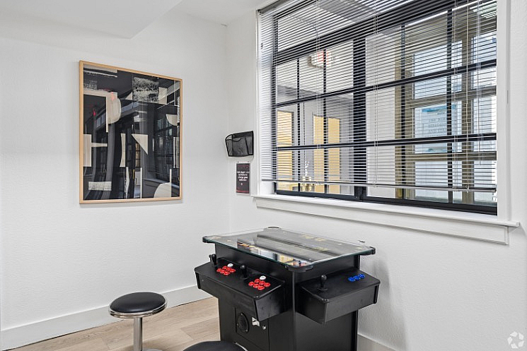 Game room corner with a sleek arcade machine and modern artwork, perfect for entertaining and relaxation.