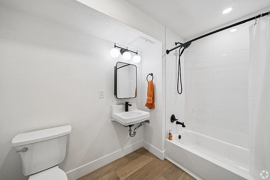 Modern bathroom design featuring sleek fixtures, a chic vanity with illuminated mirror, and a stylish shower-tub combination.