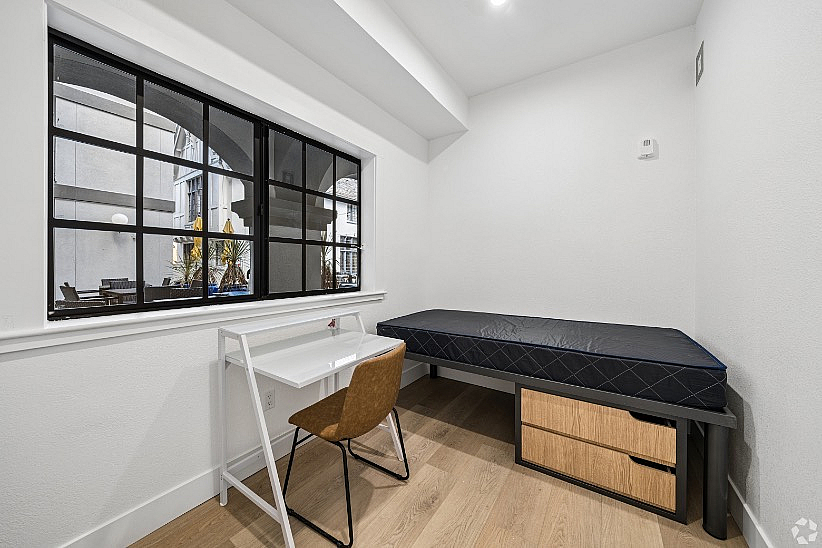 Bright study-bedroom with large window, sleek modern desk, and cozy single bed offering functional minimalism and style.