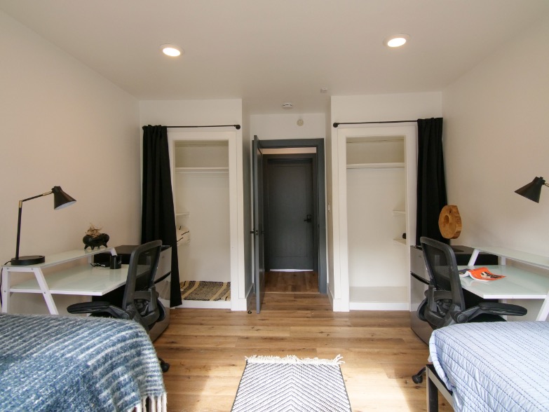 Modern shared bedroom with dual study desks and ample closet space, ideal for a student living environment.