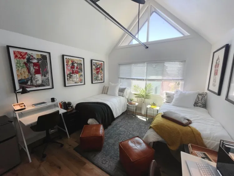 Bright and cozy twin bedroom with large triangular window, stylish decor, and a functional study area.