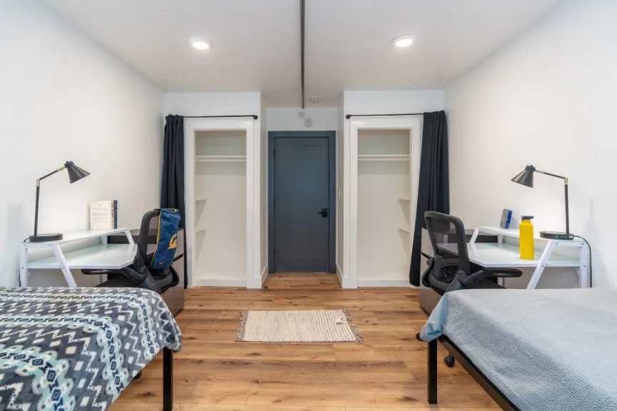 Modern dual desk bedroom featuring sleek workspaces, cozy beds, and ample closet space with elegant lighting.