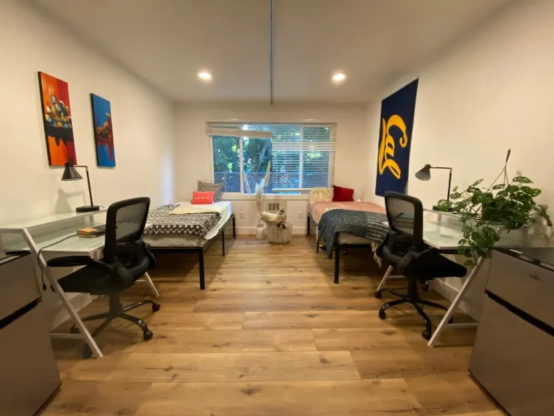 Inviting and modern double bedroom with twin beds, bright natural light, and streamlined desks, perfect for shared living.