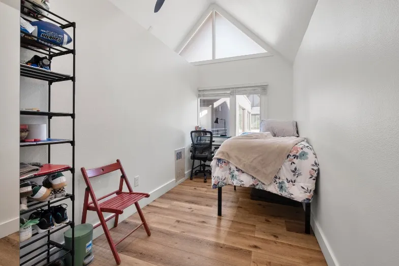 Bright and cozy bedroom featuring a single bed, stylish wooden flooring, and a large window with natural light.