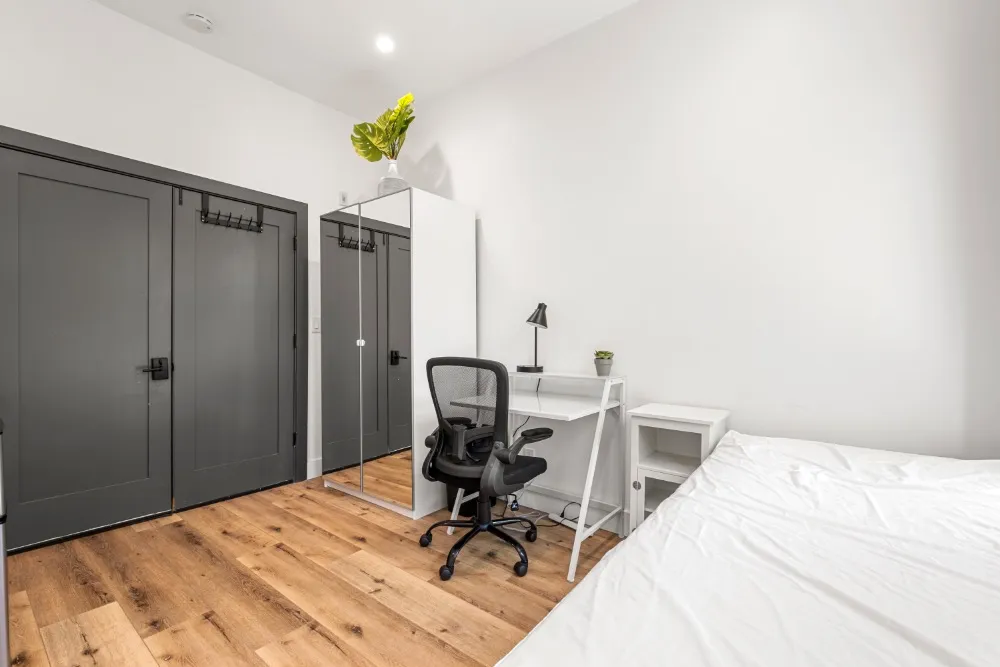 Contemporary bedroom with stylish charcoal doors, sleek workspace, and wooden flooring, perfect for a modern living experience.