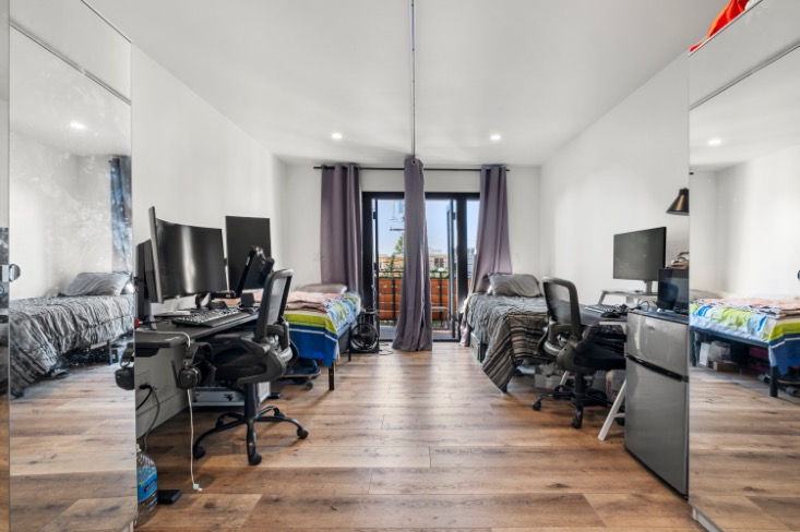 Modern bedroom with dual workstations, mirrored wardrobes, and a balcony view, perfect for shared living.