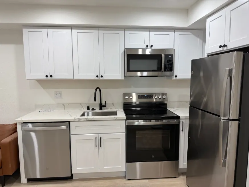 Modern kitchen with sleek stainless steel appliances, pristine white cabinetry, and elegant marble countertops.