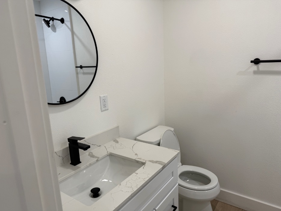 Modern bathroom with sleek black fixtures, a round mirror, and elegant marble countertop.