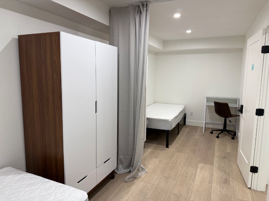 Elegant bedroom with cozy furnishings, featuring a comfortable bed, modern wardrobe, and a sleek study area with chair.