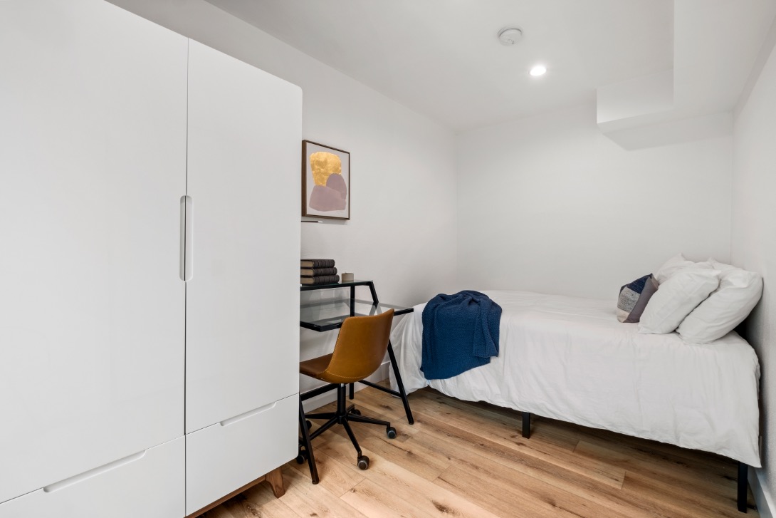 Chic and cozy bedroom featuring a minimalist design, white wardrobe, and elegant wooden flooring.