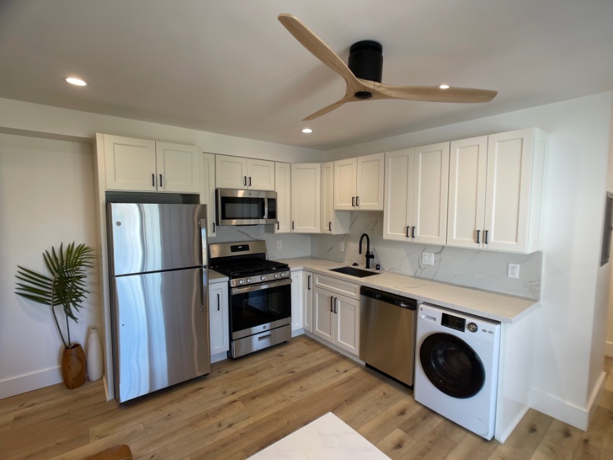 Modern kitchen with sleek white cabinetry, stainless steel appliances, and integrated washer.