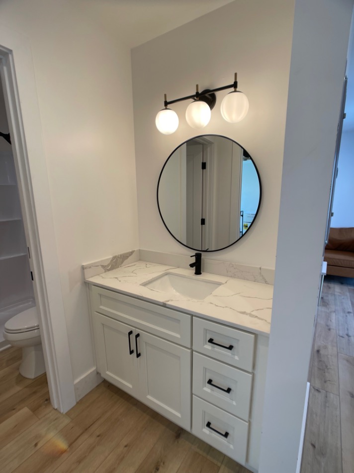 Elegant bathroom with modern vanity featuring a marble countertop, circular mirror, and stylish lighting.