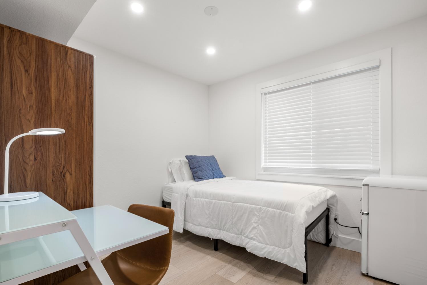 Cozy bedroom with a comfortable single bed, elegant study desk, and modern lighting, perfect for a tranquil living space.