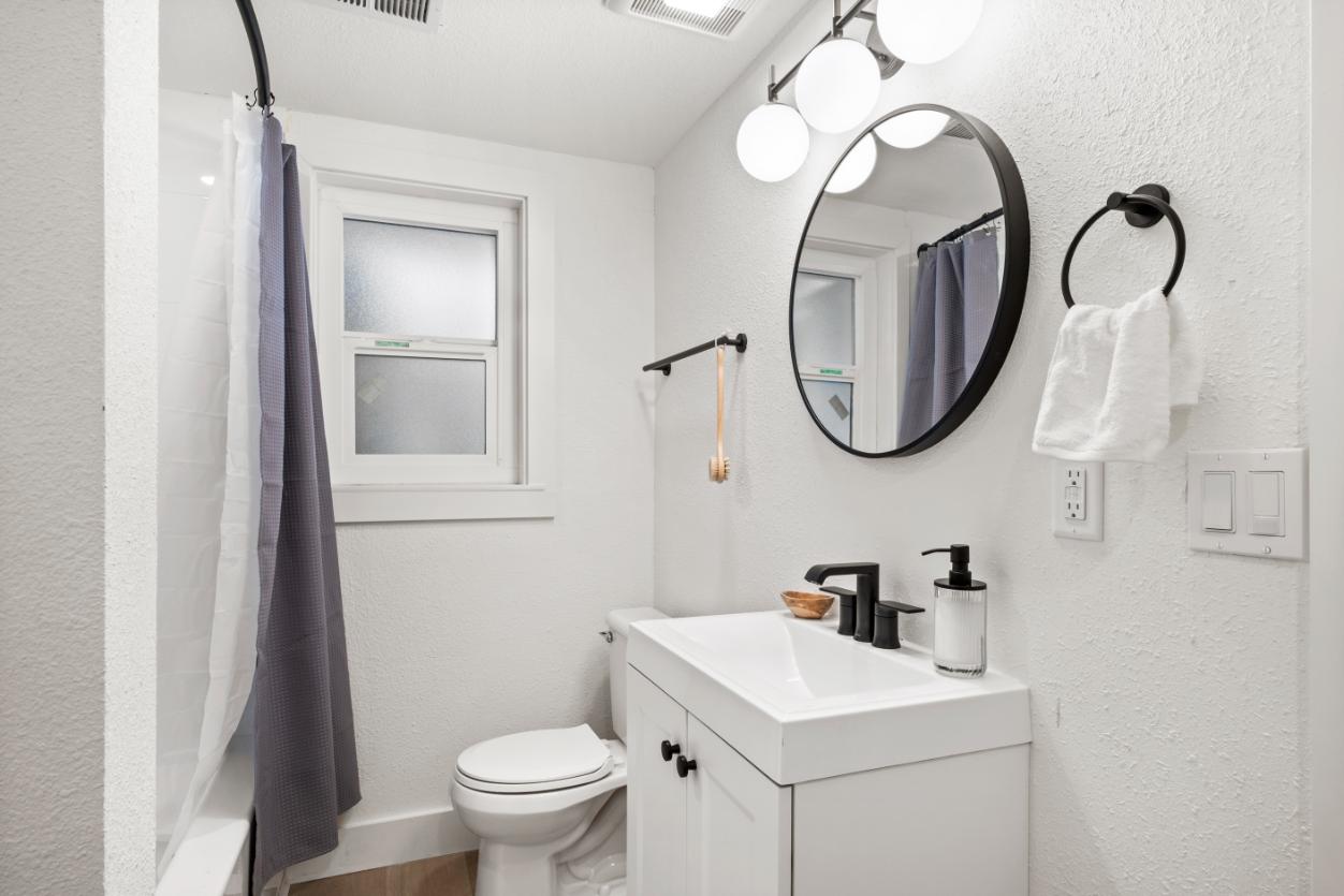 Modern bathroom featuring sleek vanity, round mirror, and stylish lighting with neutral tones.