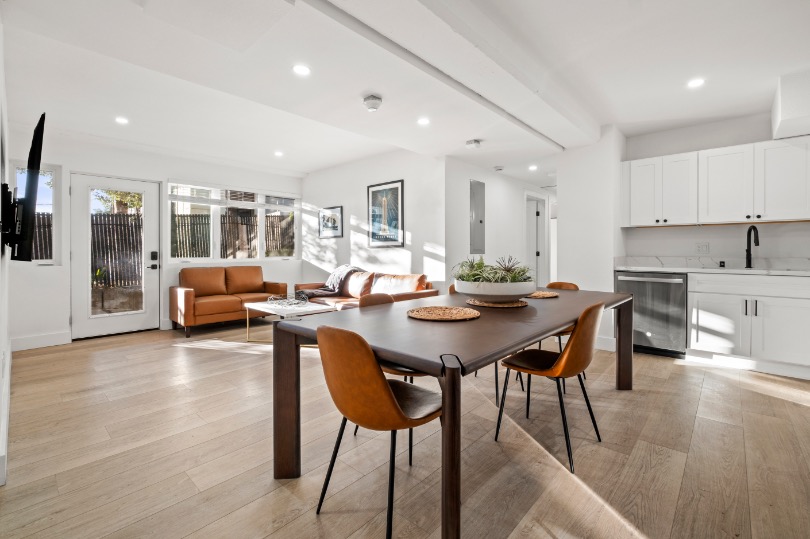 Contemporary open-concept living and dining area with sleek wood flooring, modern furnishings, and a minimalist kitchen design.