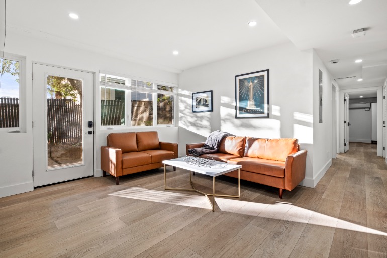 Bright and inviting living room with stylish leather sofas, modern decor, and large windows offering natural light.