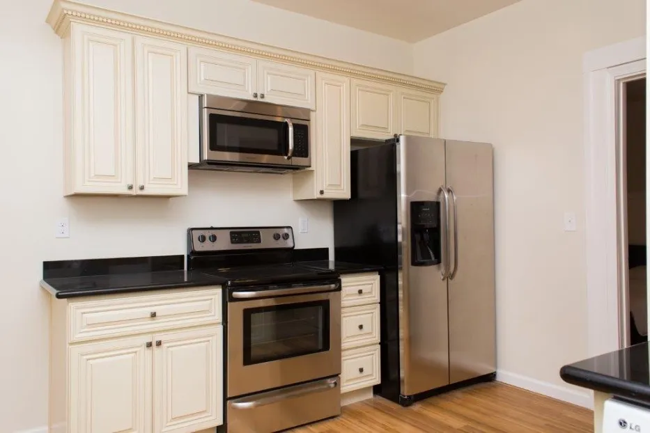 Elegant kitchen with cream cabinetry, stainless steel appliances, and warm wooden flooring.