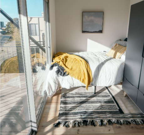 Bright and cozy bedroom with natural light, featuring a plush bed, modern wardrobe, and scenic window view.