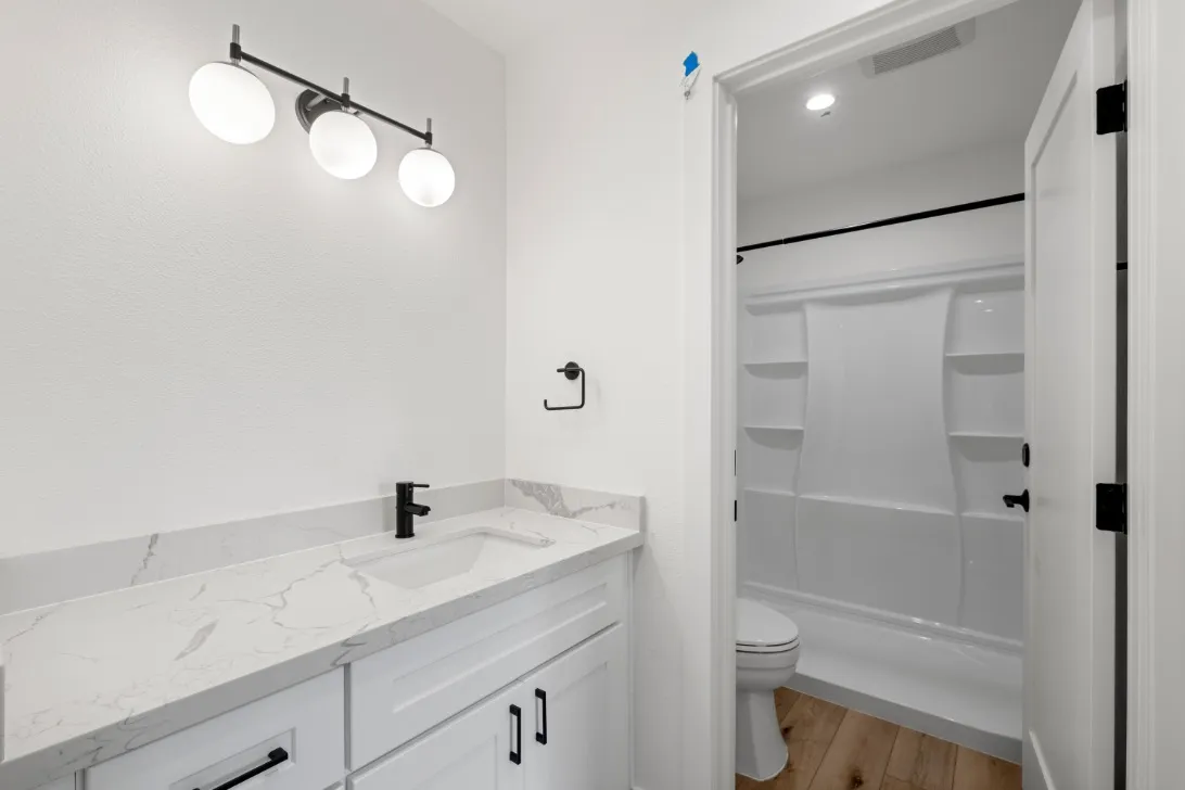 Modern bathroom with elegant white marble countertop, sleek black fixtures, and a spacious shower area.