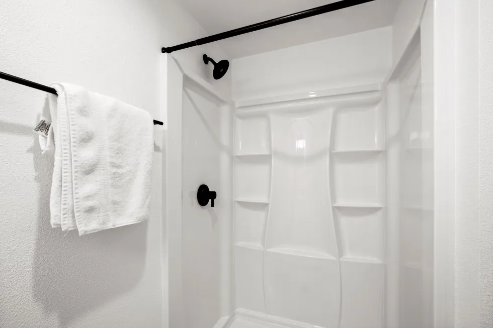 Modern white bathroom with a sleek shower, featuring elegant black fixtures.