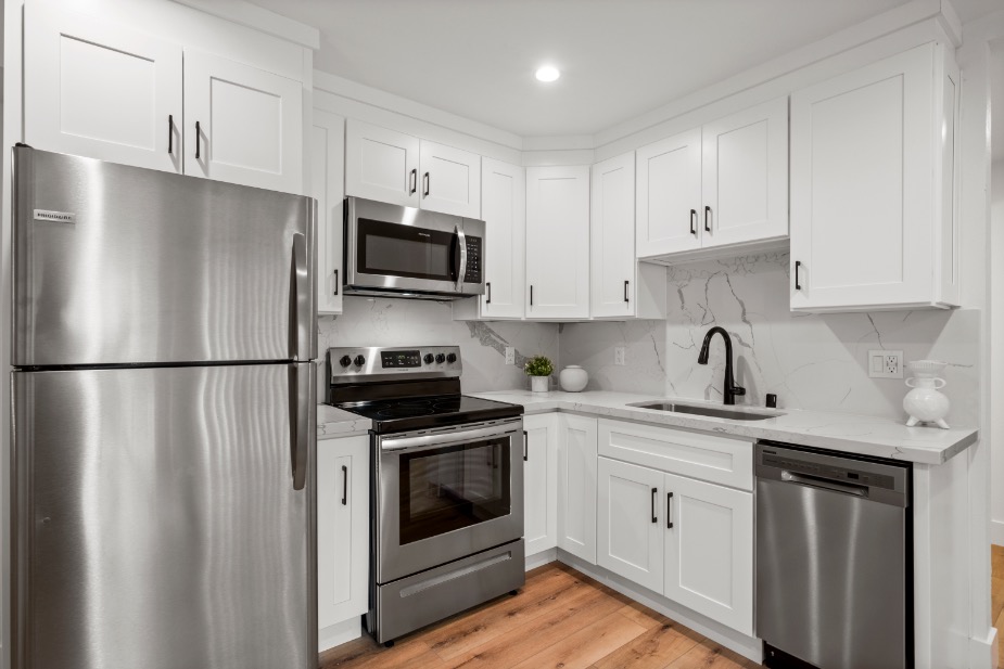 Modern kitchen with sleek stainless steel appliances, white cabinetry, and elegant marble countertops.