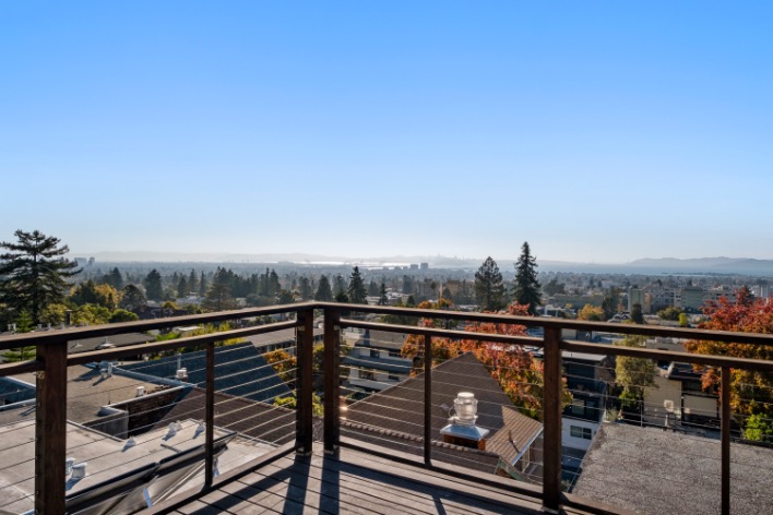 Breathtaking balcony view overlooking a picturesque cityscape with lush greenery and a clear blue sky.