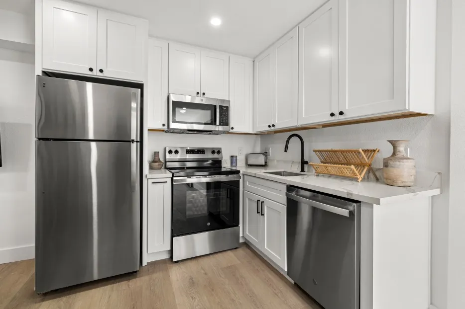 Modern kitchen with sleek stainless steel appliances, white cabinetry, and elegant countertops.